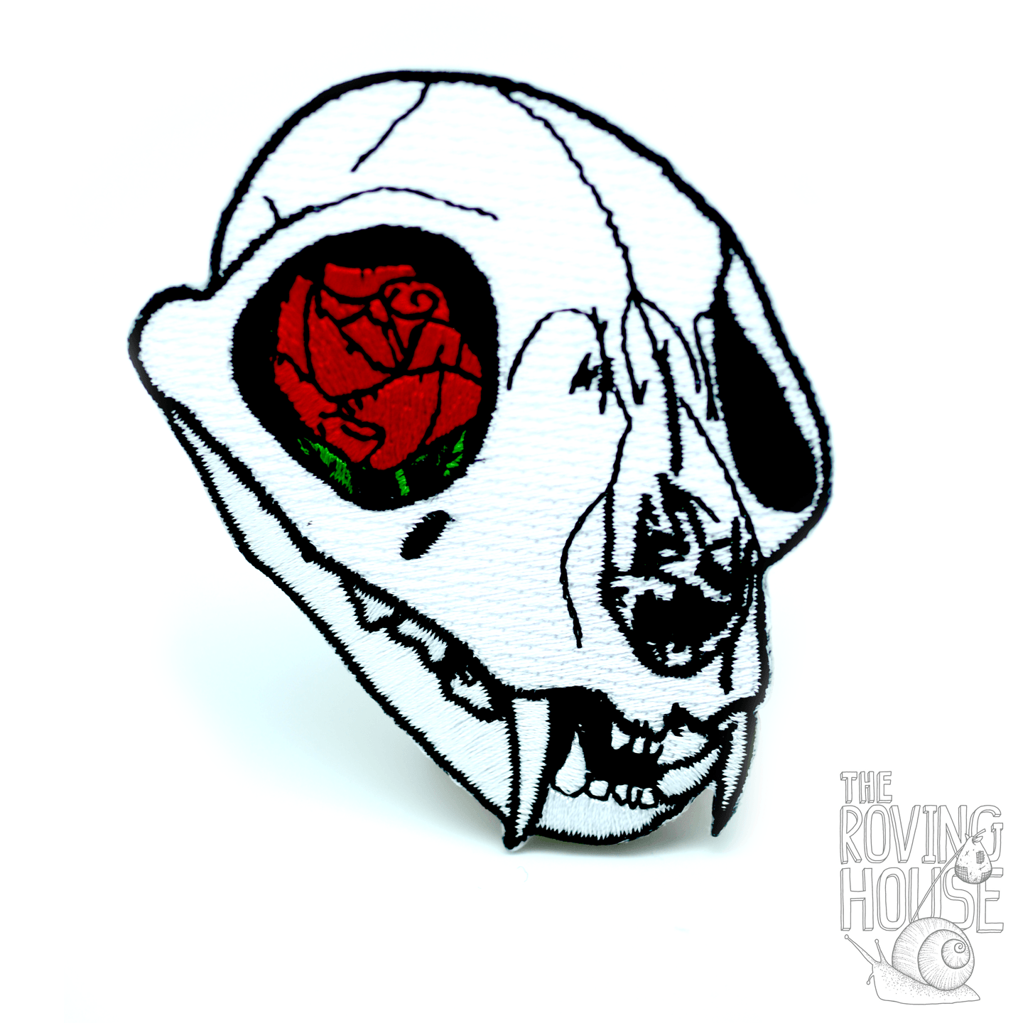 A black and white embroidered patch of a cat skull with a red rose in its eye socket.