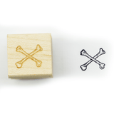 A wood and rubber stamp of crossbones, next to its inked stamped artwork.