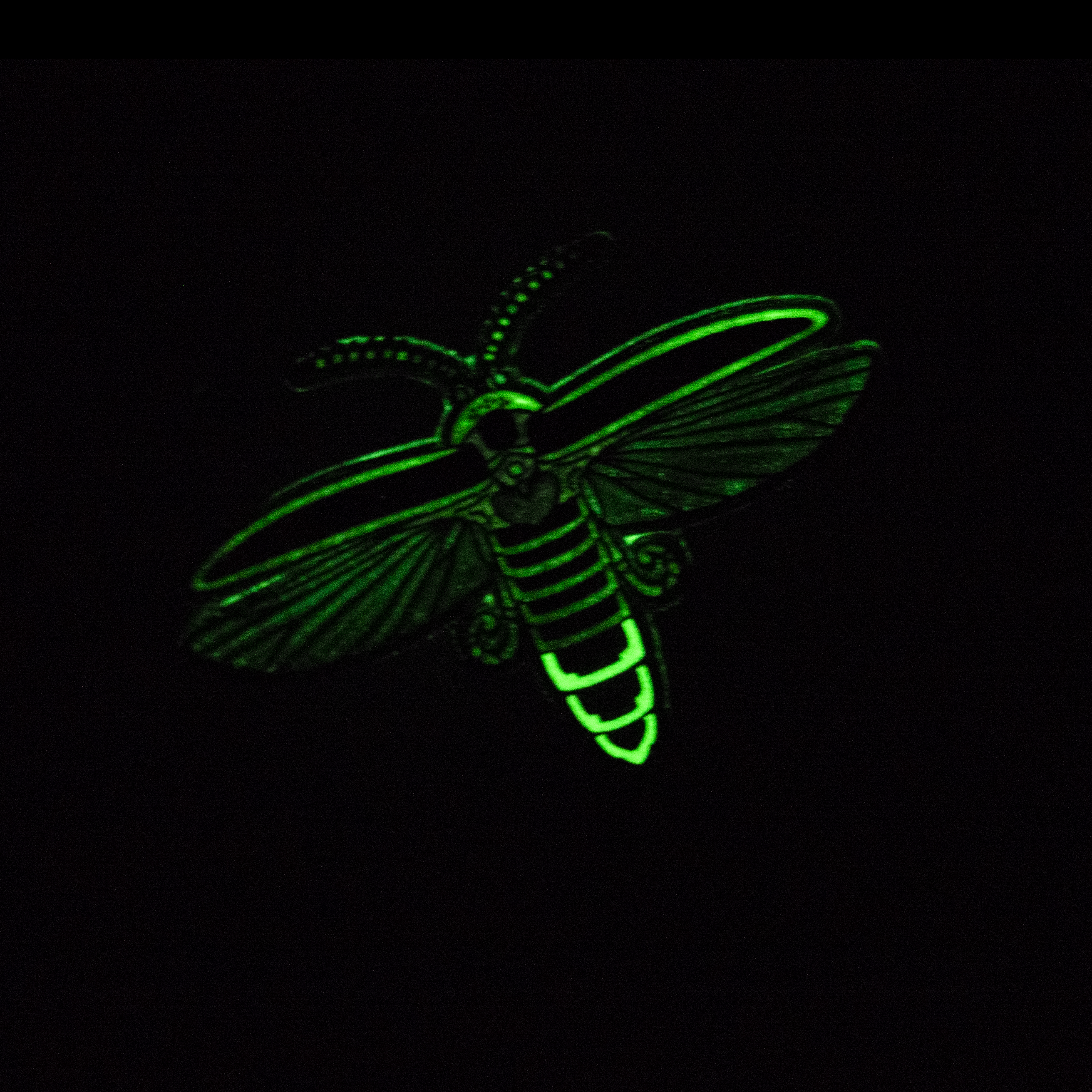 A big dipper firefly enamel pin glowing in the dark.