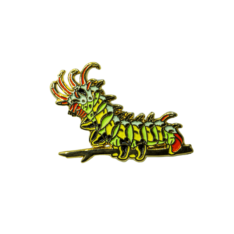 A green, yellow, black, orange, blue, and gold enamel pin of the Citheronia Regalis caterpillar, the Hickory Honrned Devil, in bright white light.