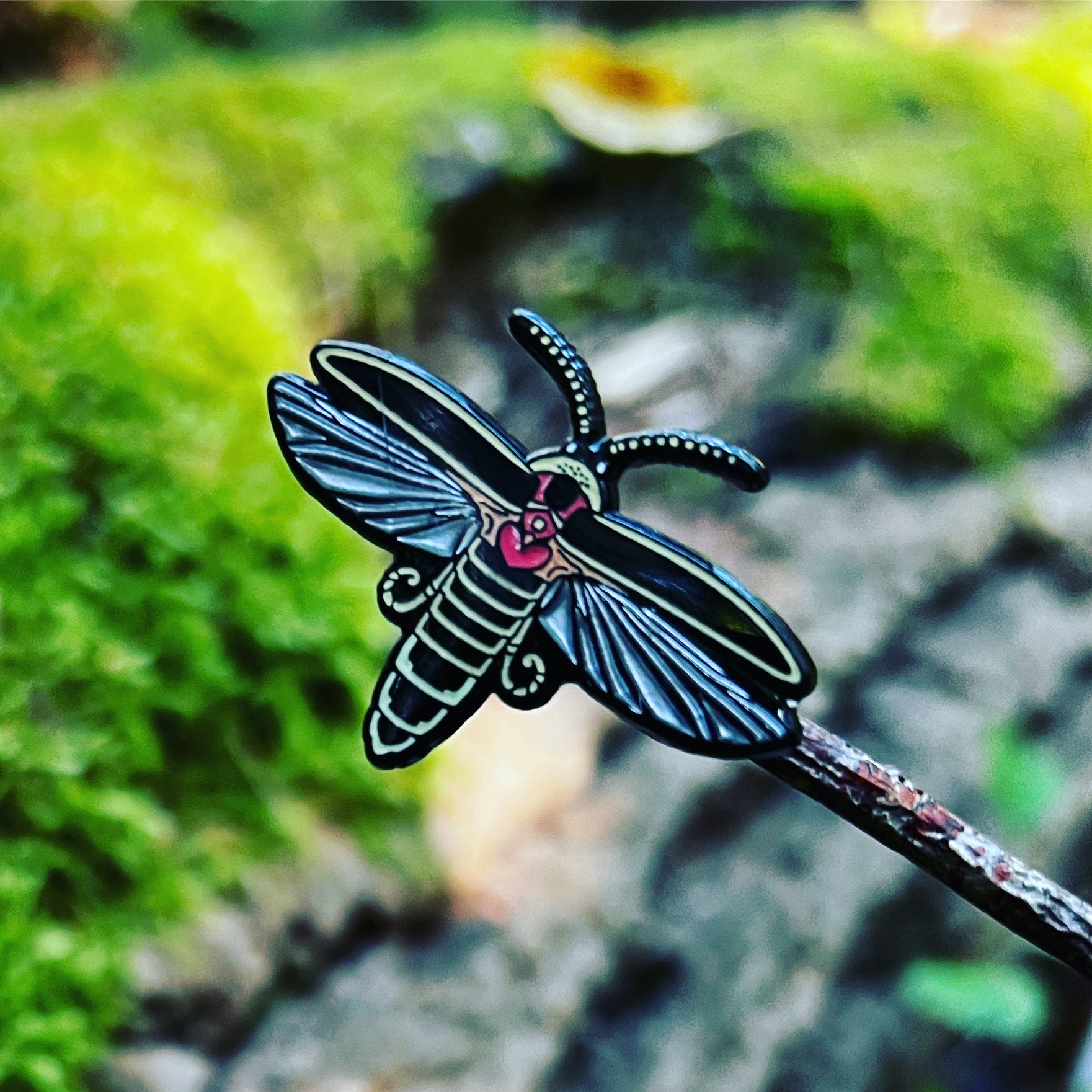 An enamel pin of a big dipper firefly with wings outstretched.