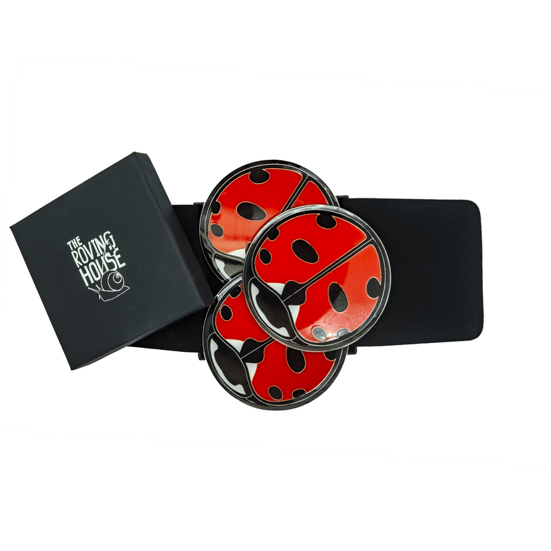 Three ladybug-patterned enamel coasters on top of an opened black jewelry box.