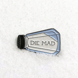 A blue, silver, and white enamel pin of a salt shaker that says "DIE MAD" on its side, sitting in a pile of salt.