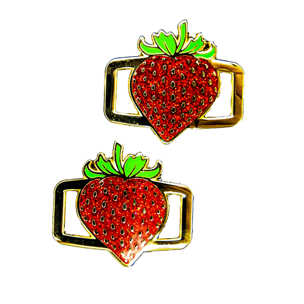 A pair of green, gold, and glitter red mirrored strawberry shoelace charms.